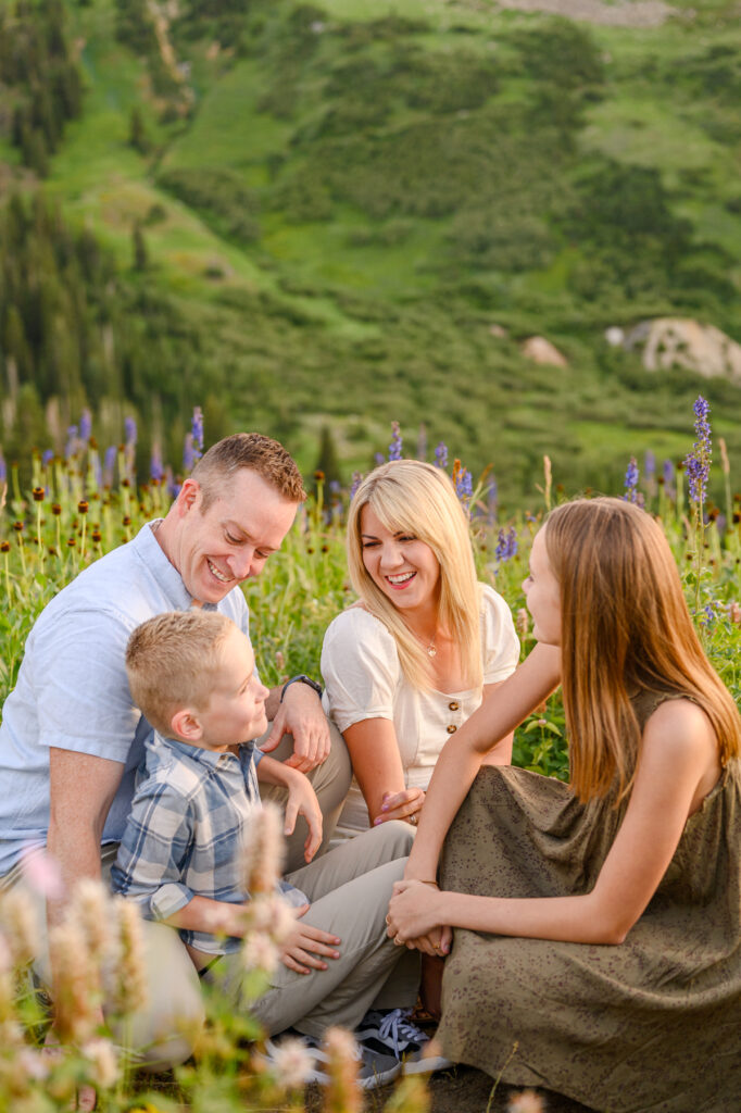 photo of a family smiling candidly in the wildflowers up little cottonwood canyon for family pictures taken by luxury utah family photographer