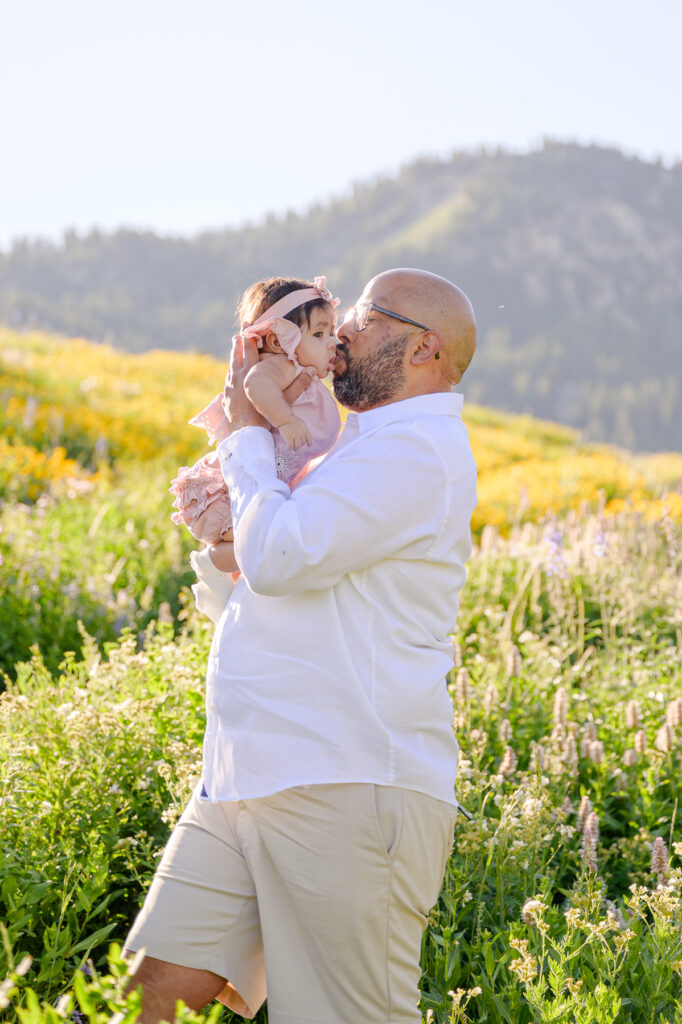photo of dad kissing baby in the wildflowers up little cottonwood canyon for family pictures taken by luxury utah family photographer