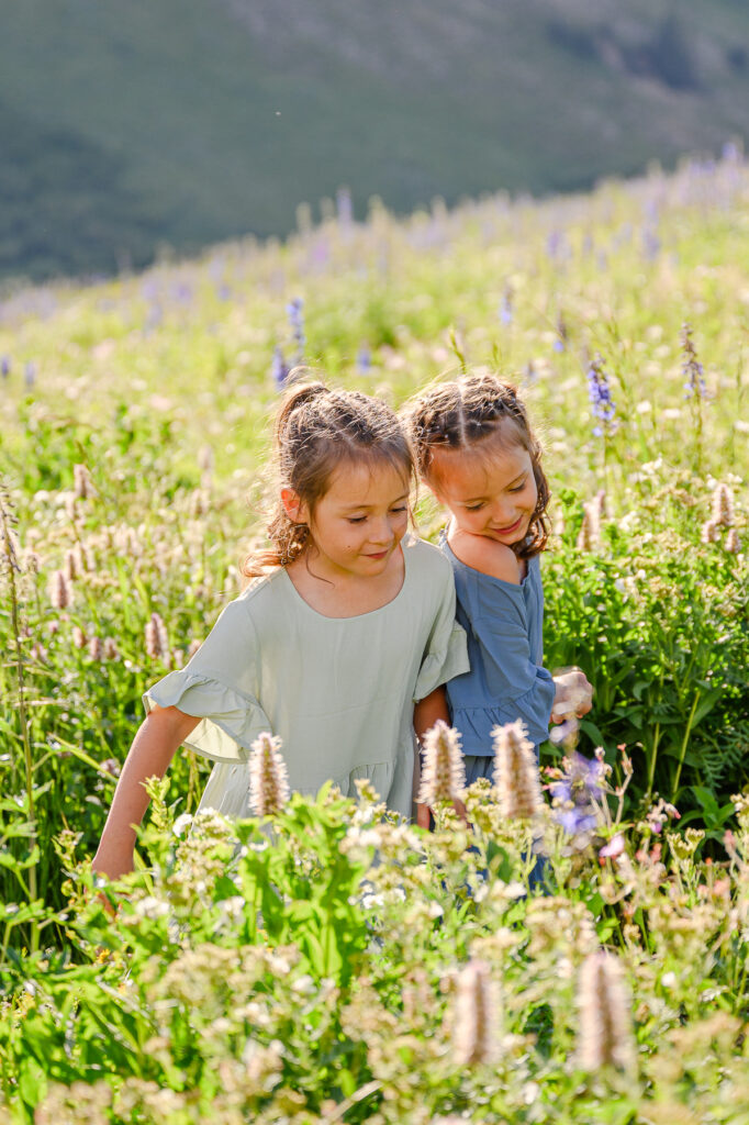 photo of two girls in the wildflowers up little cottonwood canyon for family pictures taken by luxury utah family photographer